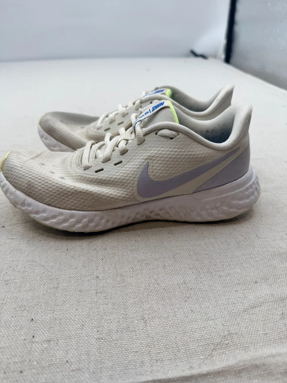 Nike Women’s Revolution Sneakers in Cream with Light Purple Swoosh